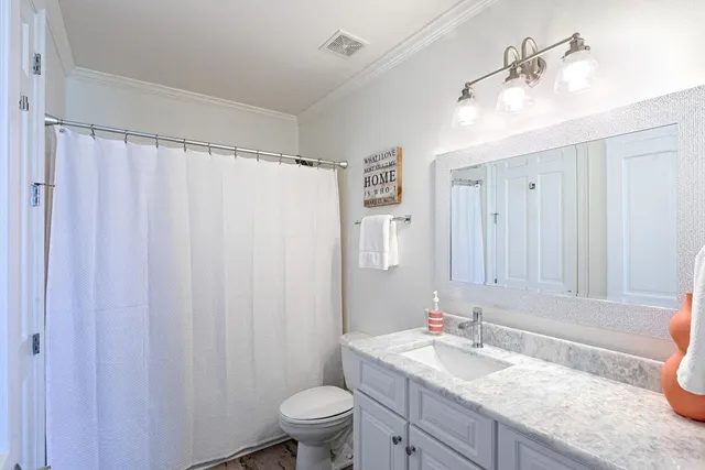 a bathroom with a granite countertop sink toilet a mirror a vanity and shower