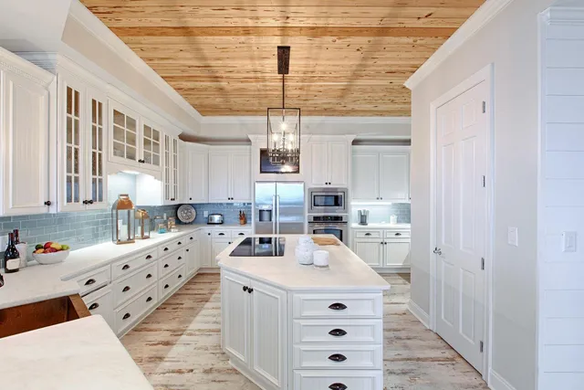 a kitchen that has a lot of white cabinets and stainless steel appliances