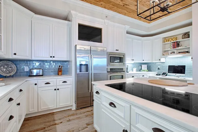 a kitchen with granite countertop a sink stainless steel appliances and white cabinets