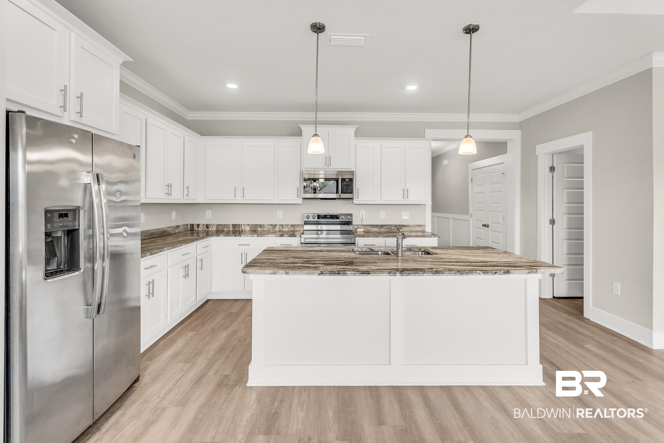1720 Partridge Street Foley, AL 36535 - Photo 7 of 32 Kitchen with appliances with stainless steel finishes, light hardwood / wood-style flooring, white cabinets, pendant lighting, and a center island with sink