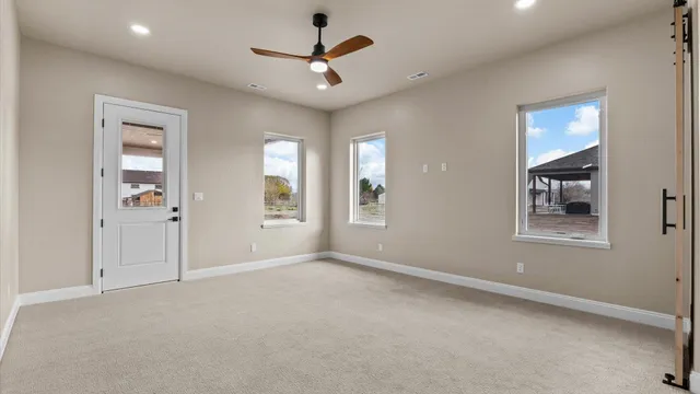an empty room with ceiling fan and windows