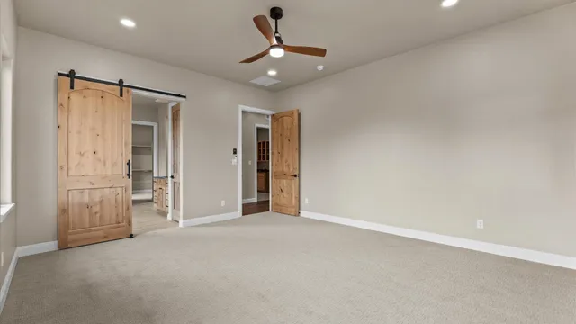 an empty room with a ceiling fan and closet area