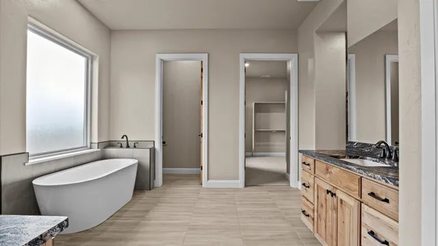 a bathroom with a granite countertop tub sink a mirror and a bathtub