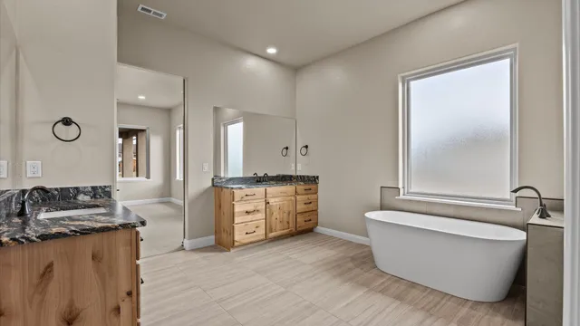 a spacious bathroom with a double vanity sink a mirror and a bathtub