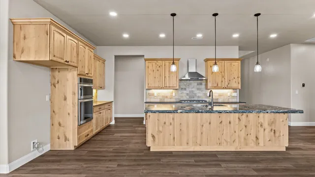 a kitchen with stainless steel appliances granite countertop a kitchen island hardwood floor and a sink