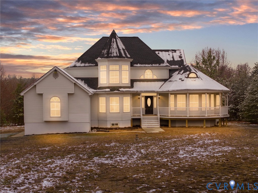 Back of property at dusk with covered porch and a