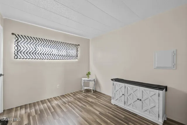 a view of an empty room with wooden floor and a bathroom