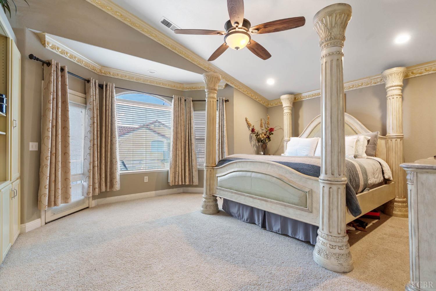 960 Vista Place Lemoore, CA 93245 - Photo 25 of 34 a spacious bedroom with a large bed and a chandelier