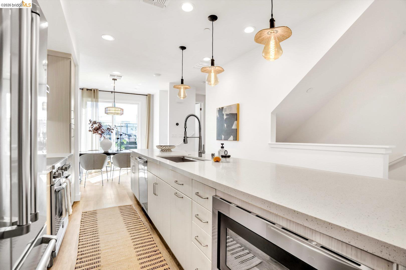 2229 Myrtle Street Oakland, CA 94607 - Photo 7 of 37 kitchen featuring a center island with sink, light wood finished floors, stainless steel appliances, pendant lighting, and decorative backsplash