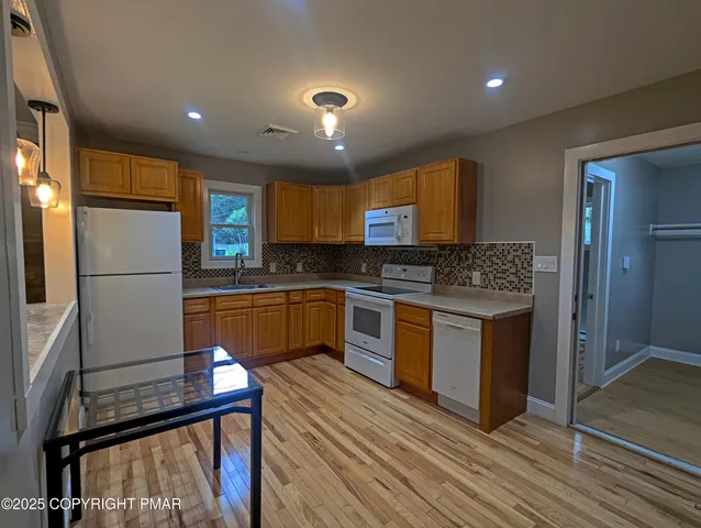 a kitchen with granite countertop a refrigerator stove top oven and sink