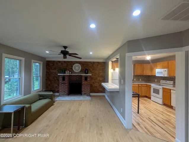 a large living room with stainless steel appliances kitchen island granite countertop a large window and a couch