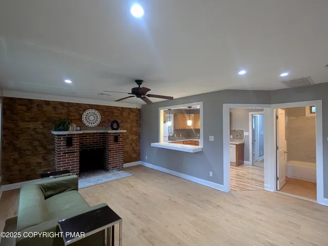 a view of an empty room and a kitchen with furniture wooden floor and a fireplace