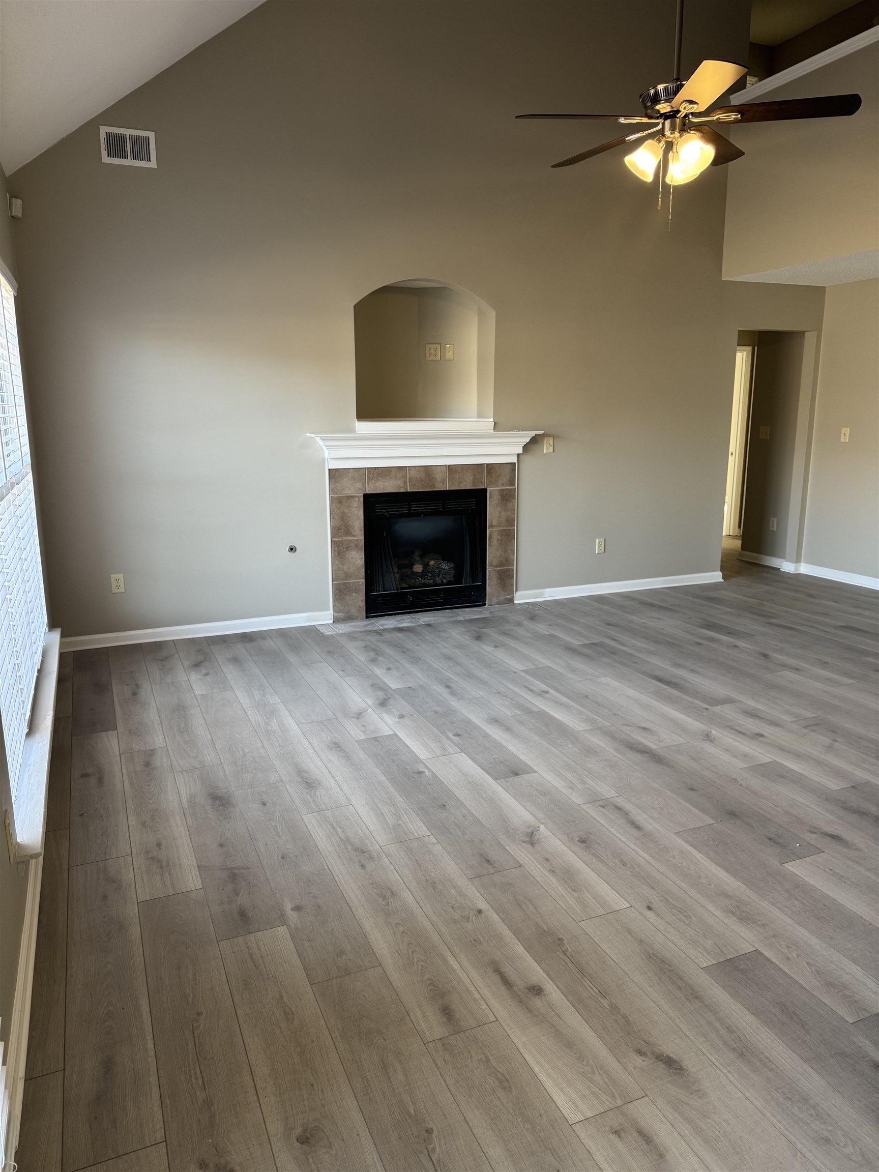 4929 Whitfall Cove South Memphis, TN 38125 - Photo 22 of 22 an empty room with wooden floor fireplace and fan