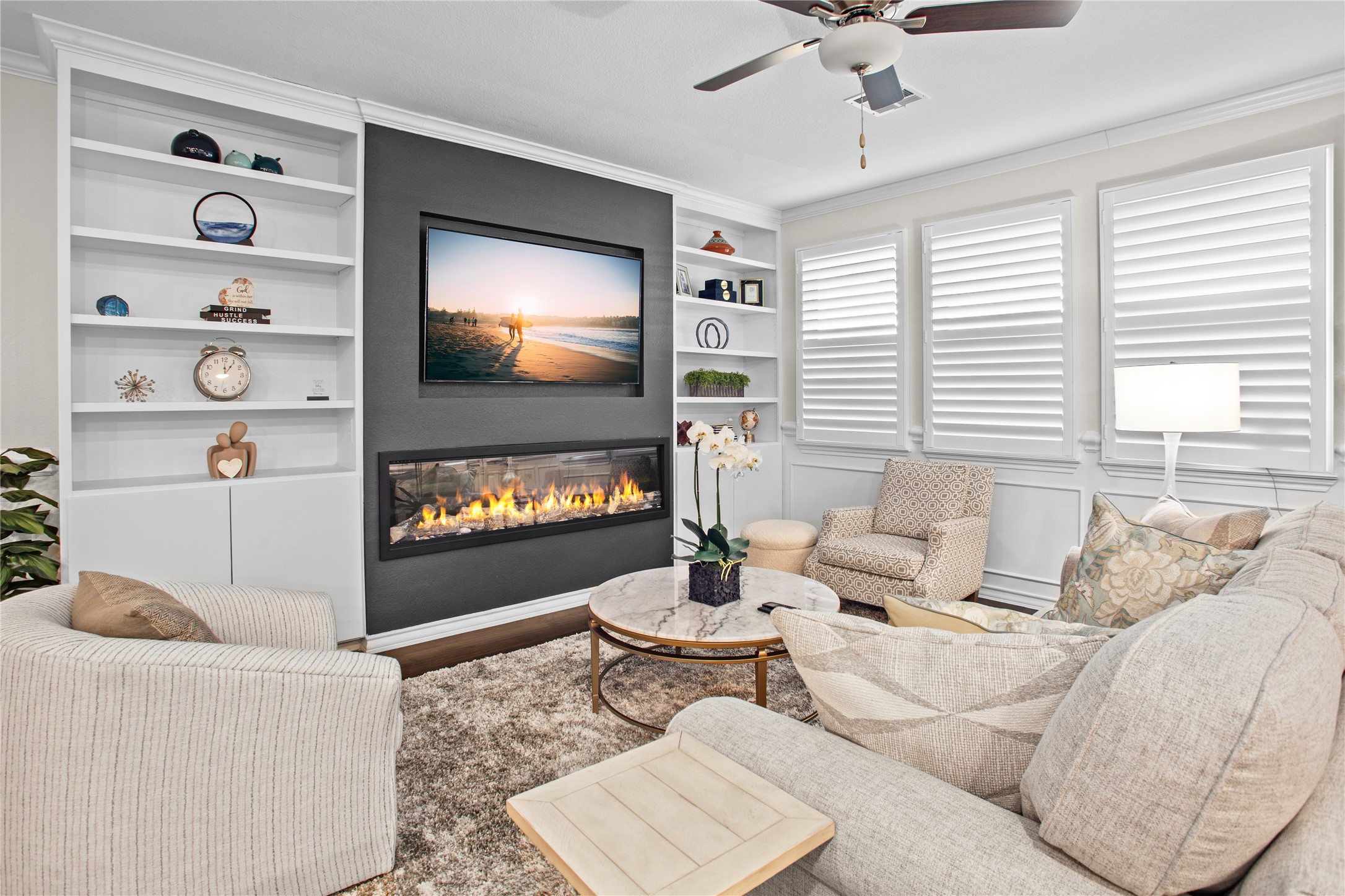 109 Adeline Road Hutto, TX 78634 - Photo 15 of 40 Living room with built in shelves, a glass covered fireplace, ceiling fan, crown molding, and wood finished floors