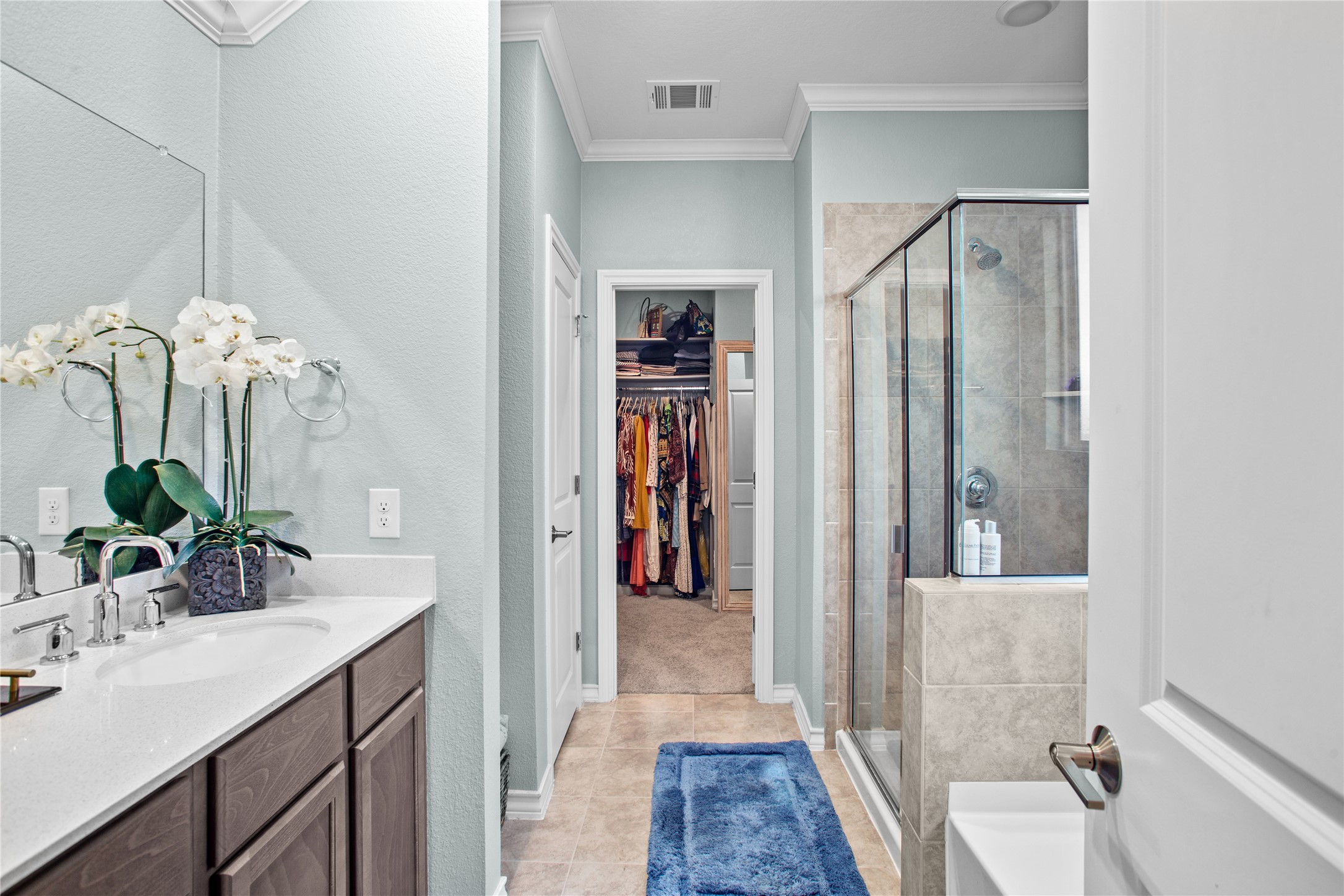 109 Adeline Road Hutto, TX 78634 - Photo 20 of 40 Full bathroom featuring vanity, a stall shower, crown molding, a walk in closet, and light tile patterned floors