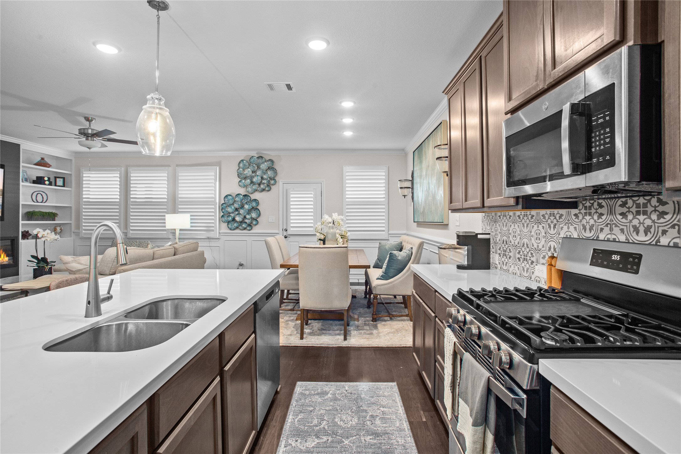 109 Adeline Road Hutto, TX 78634 - Photo 40 of 40 Kitchen with stainless steel appliances, dark wood finish cabinetry, open floor plan, a ceiling fan, and ornamental molding