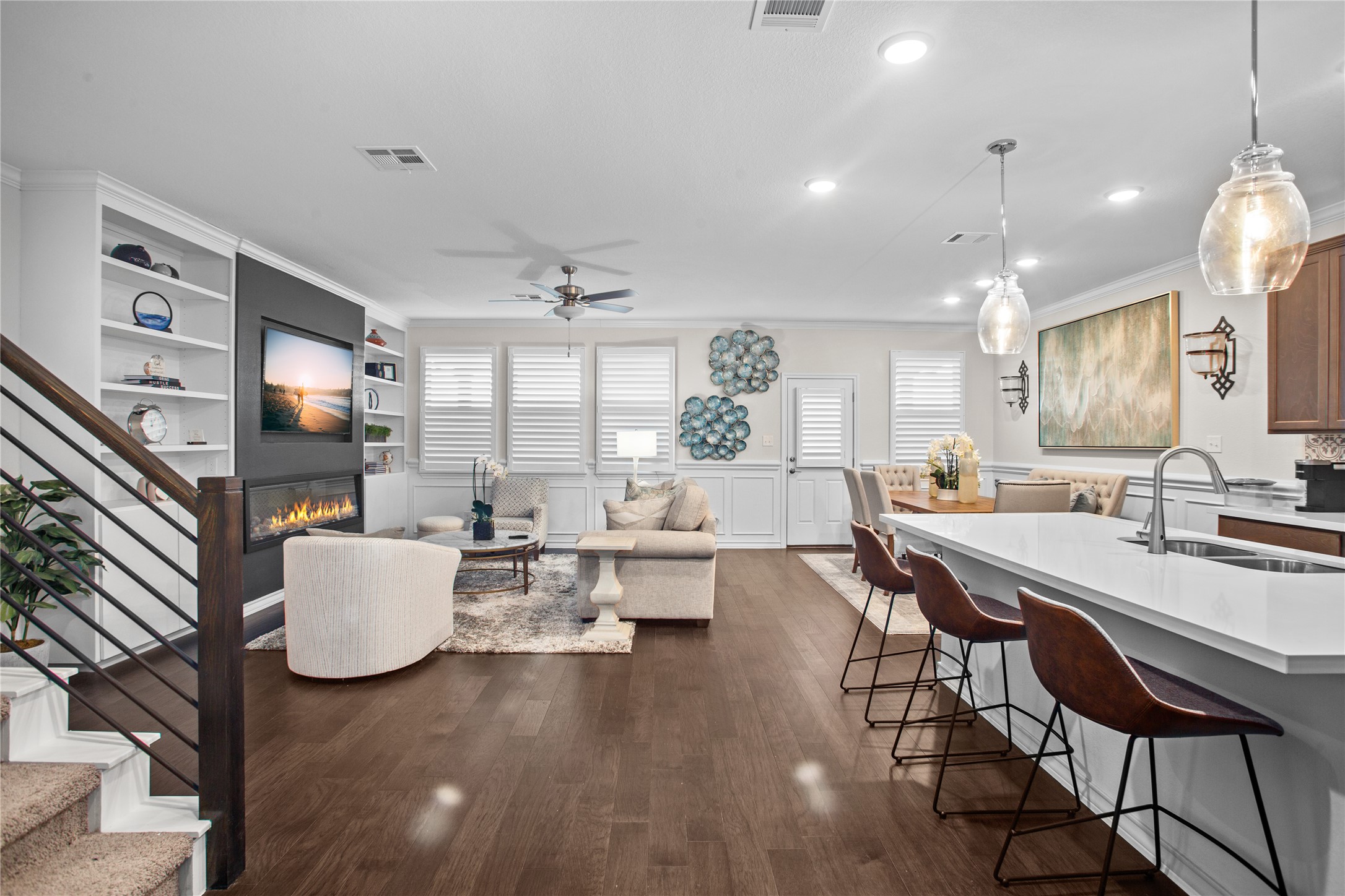109 Adeline Road Hutto, TX 78634 - Photo 7 of 40 Living area with built in shelves, ornamental molding, dark wood-style flooring, a glass covered fireplace, and a ceiling fan