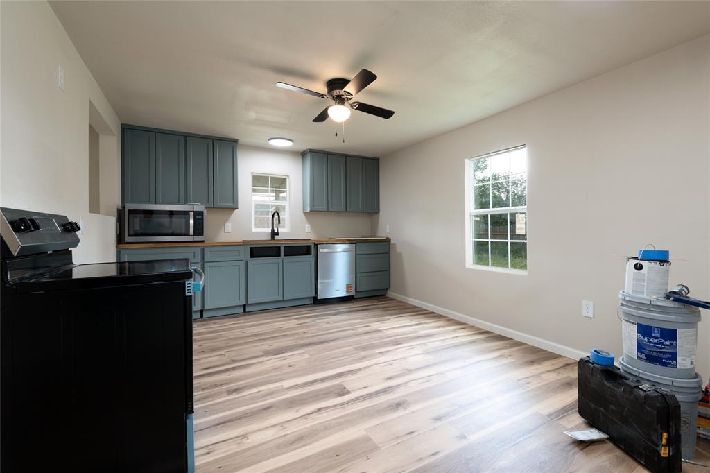 3001 Old Anson Road Abilene, TX 79603 - Photo 6 of 16 Spacious kitchen featuring sage cabinetry, wood-finish flooring, a black range, stainless steel microwave, and a ceiling fan with integrated lighting
