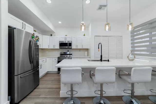 a kitchen with stainless steel appliances a refrigerator a stove a sink a dining table and chairs