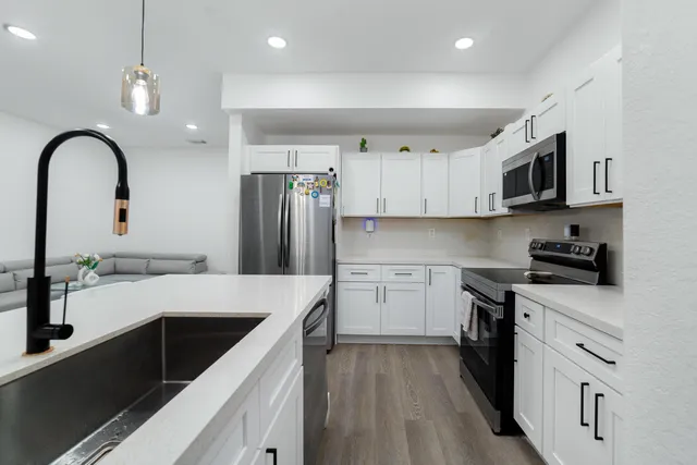 a kitchen with a sink white cabinets and stainless steel appliances