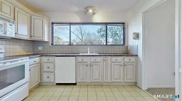 a kitchen with white cabinets a window and a sink