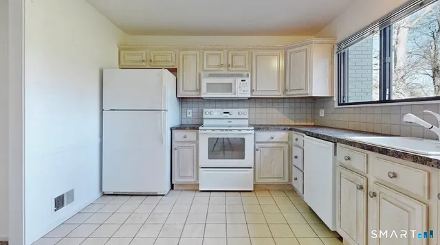 a kitchen with white cabinets and white appliances