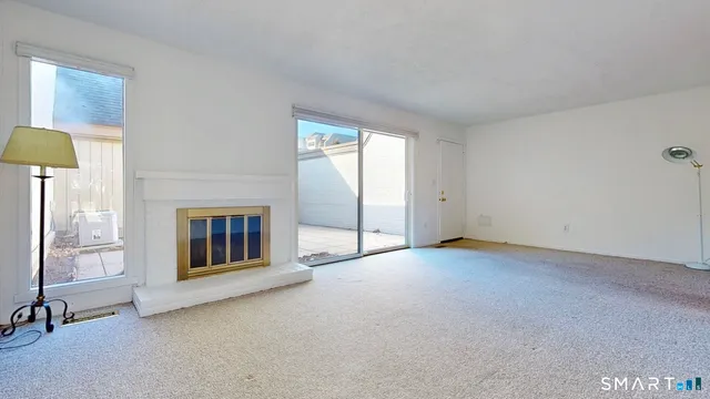 an empty room with windows and fireplace