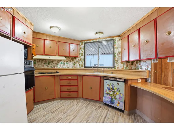 a kitchen with stainless steel appliances granite countertop a refrigerator a sink dishwasher and wooden cabinets with wooden floor