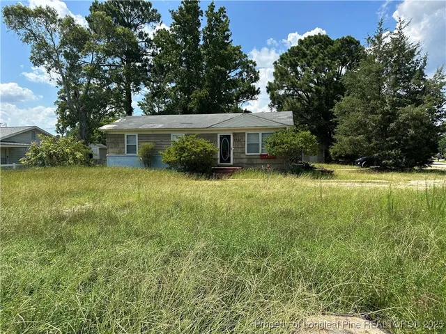 a view of a house with a yard and large trees