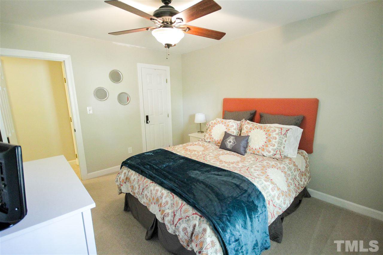 8212 Hambledon Court Raleigh, NC 27615 - Photo 12 of 28 a bedroom with a bed and a chandelier