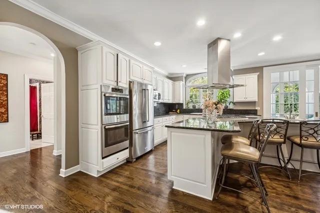 a kitchen with granite countertop white cabinets and white appliances with wooden floor