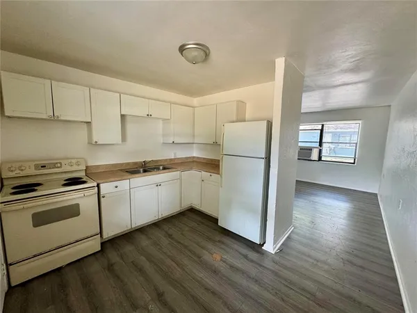 a kitchen with a refrigerator a stove top oven and a wooden floor