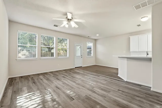 a view of empty room with wooden floor and fan
