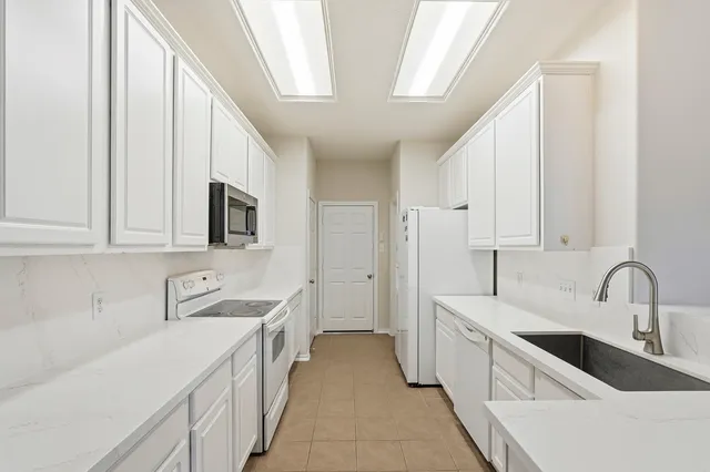 a kitchen with granite countertop a sink and white cabinets