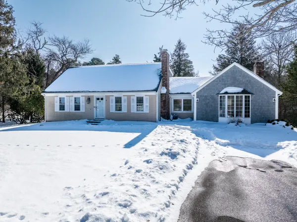 a front view of a house with a yard covered in snow