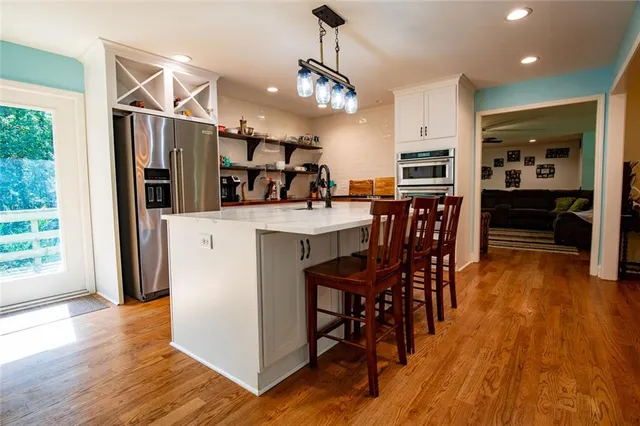 a utility room with stainless steel appliances granite countertop a sink dishwasher a refrigerator and a stove with wooden floor