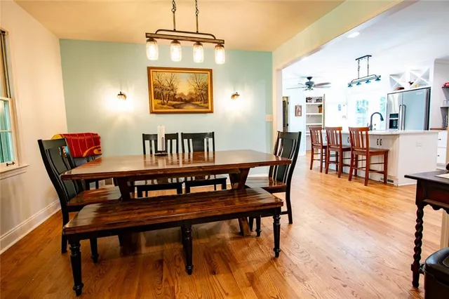 a kitchen with stainless steel appliances kitchen island granite countertop a table chairs and a wooden floor