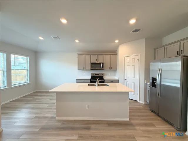 a view of kitchen with kitchen island stainless steel appliances counter space and a window