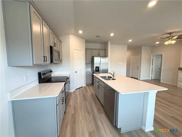 a large kitchen with stainless steel appliances a sink a stove and a refrigerator