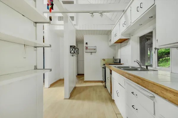 a large white kitchen with a sink and refrigerator