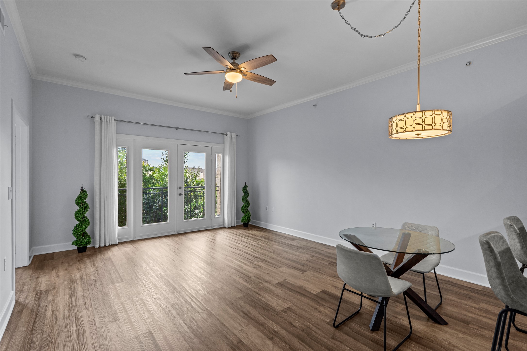 1900 Genesee Street, Unit 203 Houston, TX 77006 - Photo 6 of 30 Bright and airy living space with wood flooring, featuring large French doors that open to a balcony. The room includes a ceiling fan, modern light fixture, and space for dining.
