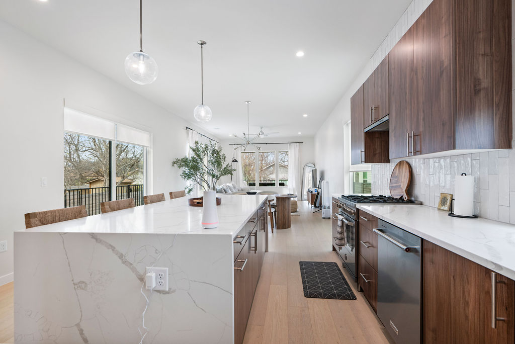 2912 East 13th Street Austin, TX 78702 - Photo 12 of 40 a large kitchen with kitchen island a large counter top space a sink stainless steel appliances and cabinets