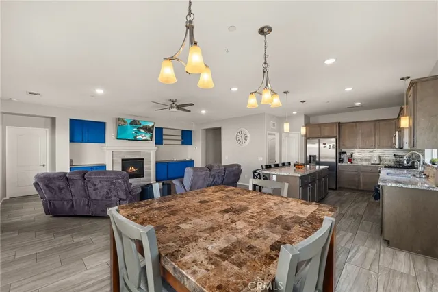 a large kitchen with stainless steel appliances granite countertop a stove a refrigerator a oven a sink a dining table and chairs with wooden floor