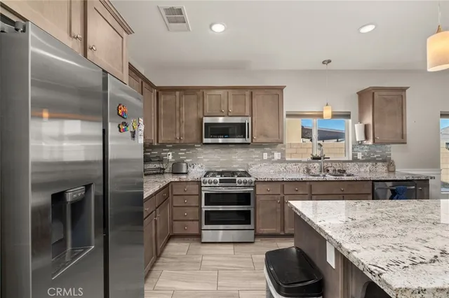 a kitchen with stainless steel appliances granite countertop a sink stove and refrigerator