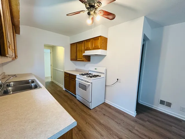 a kitchen with stainless steel appliances a stove a sink and a refrigerator with wooden floor