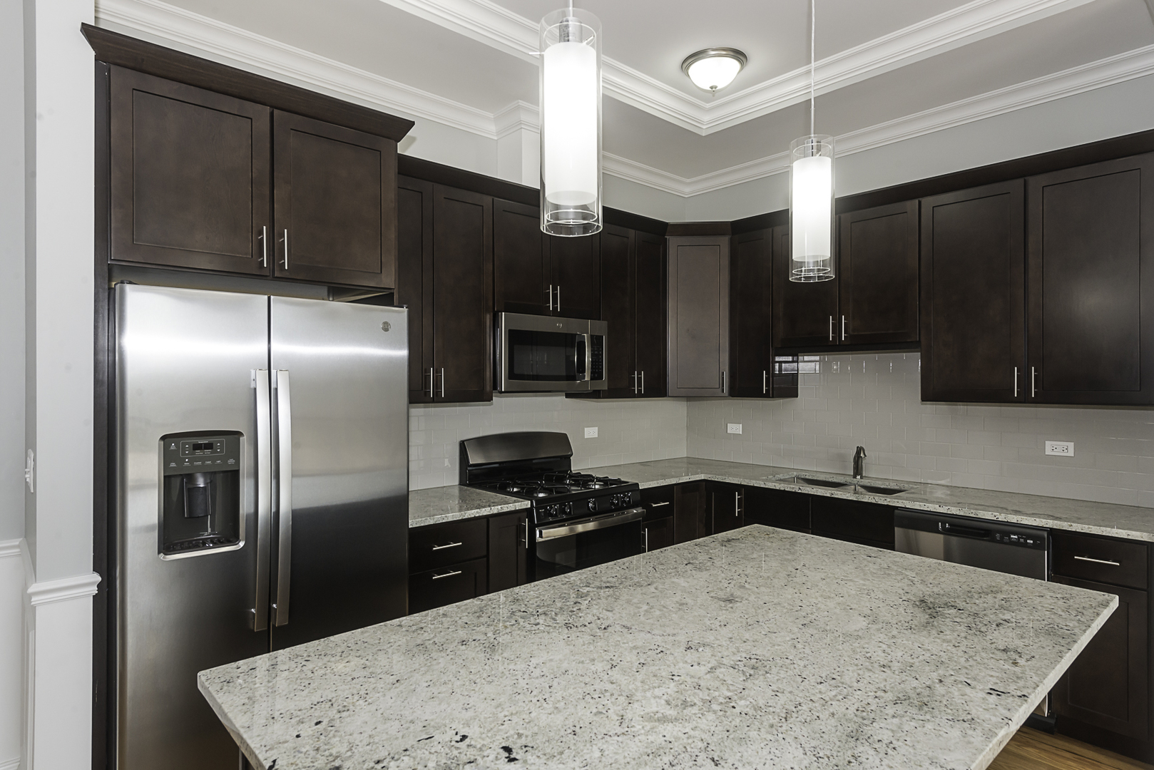 520 North Western Avenue, Unit 4B Chicago, IL 60612 - Photo 5 of 35 a kitchen with stainless steel appliances kitchen island granite countertop a refrigerator a sink and wooden cabinets