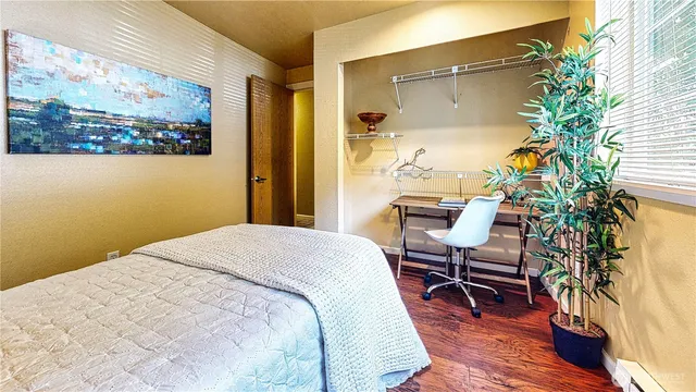 a bedroom with a bed table chair and a potted plant