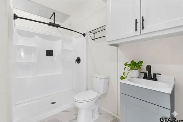 a bathroom with a sink a toilet and shower