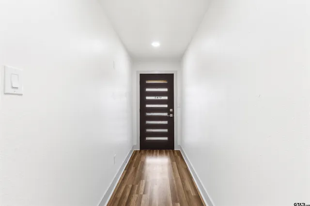 a view of an empty room with a window and kitchen view