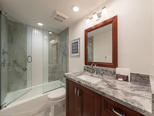 a bathroom with a granite countertop sink toilet and shower